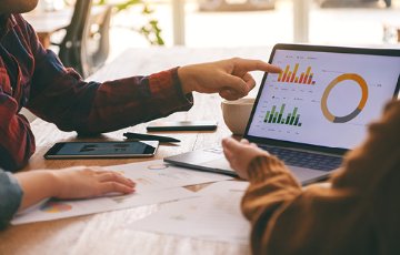 Two people evaluating data on a laptop